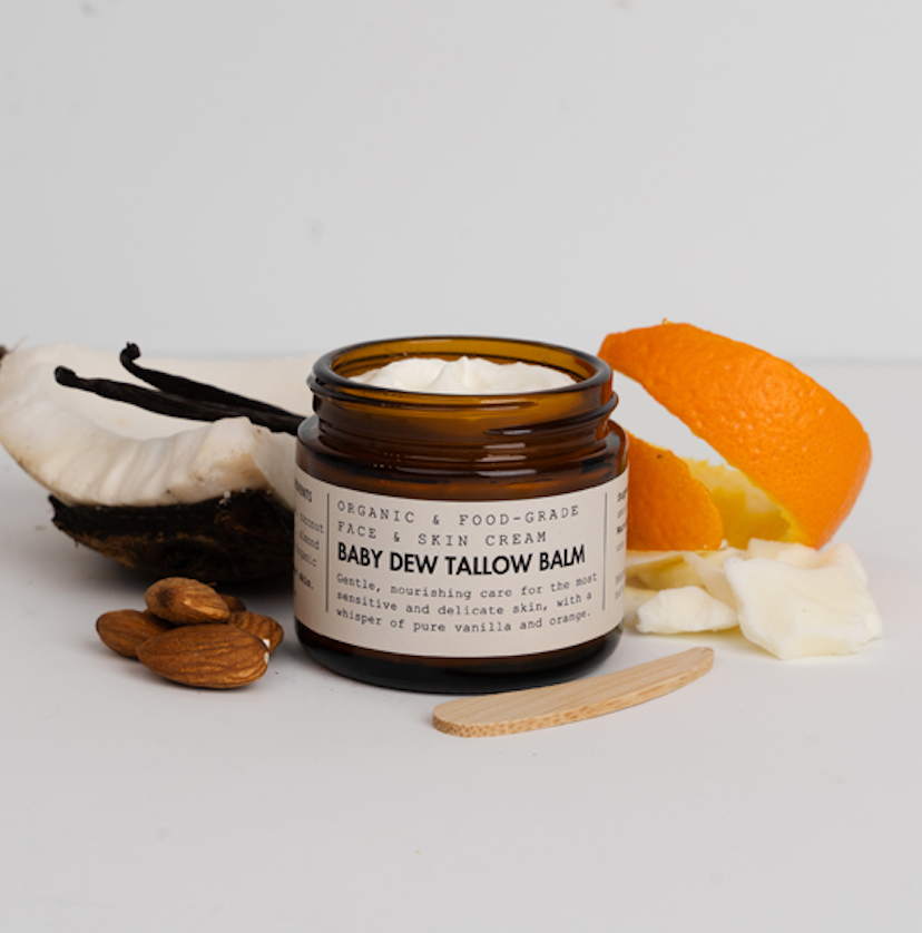 Jar of Baby Dew Tallow Balm with vanilla bean, orange, and almonds on a light background