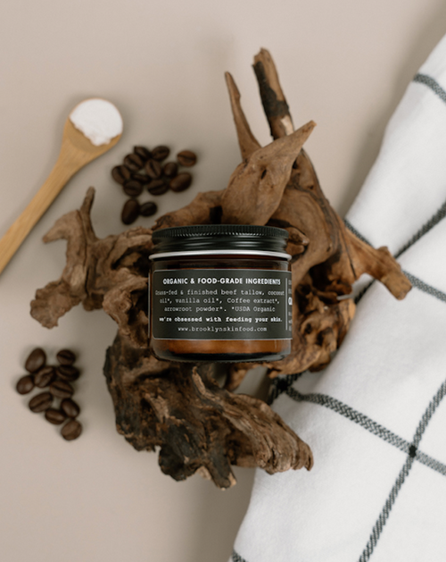 Jar of cream with coffee beans and wooden spoon on a neutral background