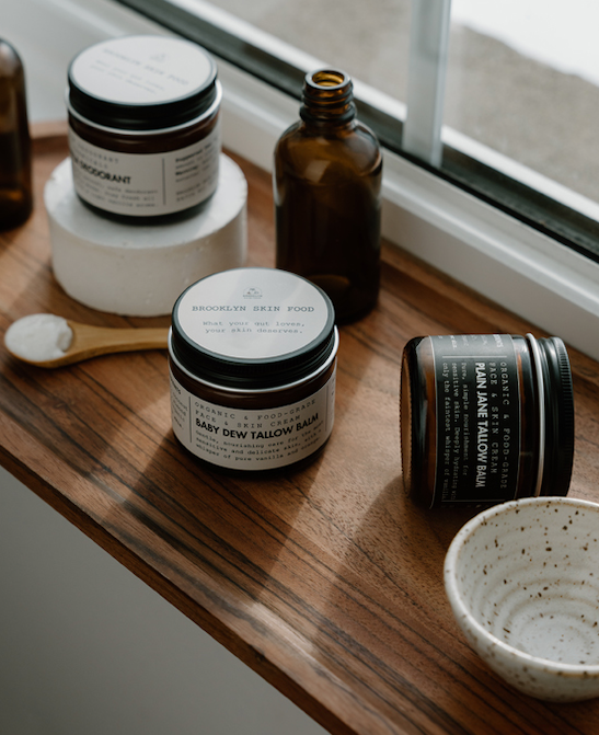 Cosmetic products including jars and bottles on a wooden surface with a window in the background.