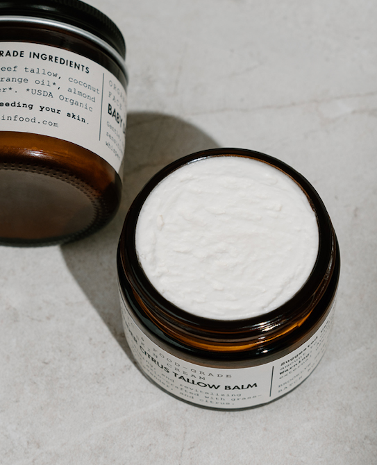 Open jar of balm with cotton swab on a textured surface